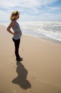 Karnı kumsalda, kimliği belirsiz hamile bir kadın. 