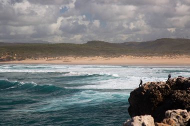Bilinmeyen balıkçılar engebeli ve aşınmış yüksek kayalıklardan Atlas Okyanusu 'na bakan bir olta kamışlarıyla avlanırlar..