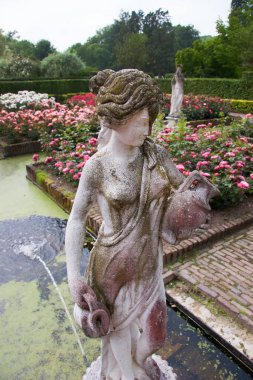 Çiçekleri, havuzu ve heykelleri olan botanik bahçesi manzarası