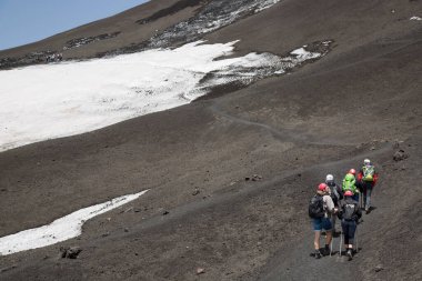 Volkanik tepelerdeki bir grup insan karla kaplı.