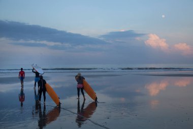 Gün batımında sahilde sörfçüler, seyahat çekimi