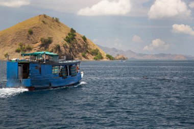 Dağlık alanda insanların gölde hareket ettiği bir tekne.