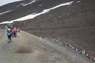 İnsanlar dağlık arazide karla yürüyüş yapıyorlar.