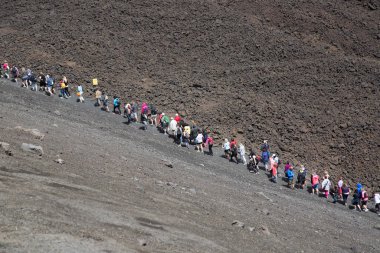 Bir grup turist güzel bir dağ manzarasında yürüyor.
