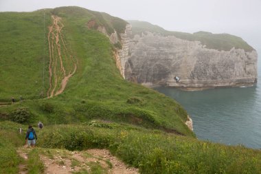 Turistler kıyı boyunca yeşil patikada yürüyorlar.