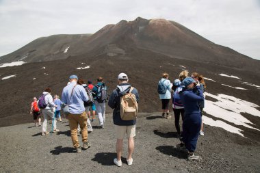 Bir grup turist güzel bir dağ manzarasında yürüyor.