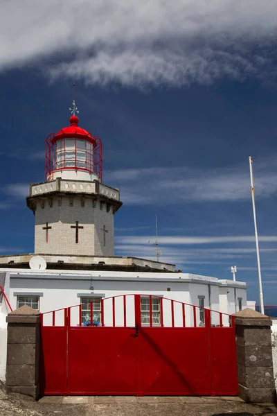 Etrafı doğal bulutlarla çevrili tarihi deniz feneri bir uçurumun tepesine ve limana uzanan dik erişim yoluna ışık hüzmesi veriyor.