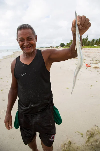 Kumsalda elinde taze balık tutan bir adam.