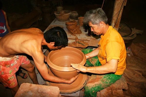 Çömlekçide kil tenceresi olan bir işçi. 