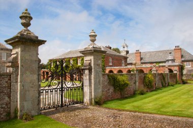 Kırsaldaki tipik bir İngiliz kır evi. Geniş çimleri ve süslemeleri olan geniş bir bahçesi var.
