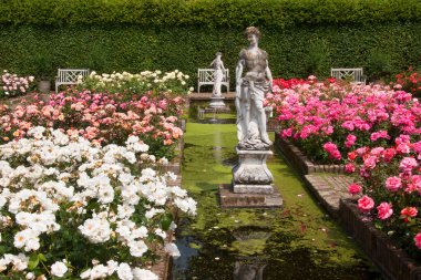 Çiçekleri, havuzu ve heykelleri olan botanik bahçesi manzarası