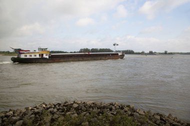 Tekne bulutlu gökyüzünün altında nehirde hareket ediyor