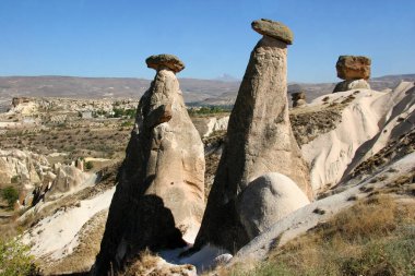 aşınmış peri bacaları ya da çıkıntılar, yukarıda dengelenen daha sert taşlar.