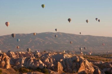 Turistlerle dolu sıcak hava balonları ulusal parkın üzerindeki volkanik bir arazide bunaltıcı manzaranın keyfini çıkarıyor.