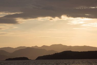 Gün batımı altında dağları olan güzel bir göl.