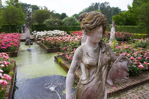 Çiçekleri, havuzu ve heykelleri olan botanik bahçesi manzarası