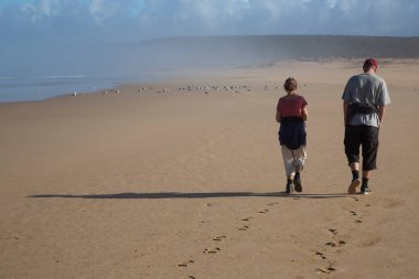 Sahilde yürüyen kadın ve erkek.