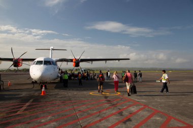 Havaalanında gün ışığında uçağı olan bir grup insan.