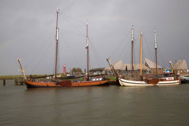 Tarihi gemiler ve balıkçı tekneleri bir IJsselmeer limanının rıhtımına demirlemiştir.