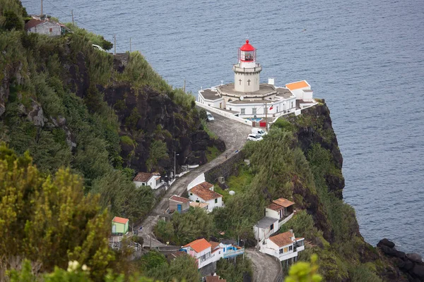 Etrafı doğal bulutlarla çevrili tarihi deniz feneri bir uçurumun tepesine ve limana uzanan dik erişim yoluna ışık hüzmesi veriyor.