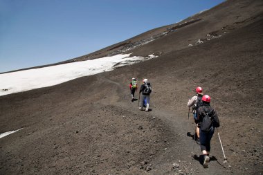 Volkanik tepelerdeki bir grup insan karla kaplı.