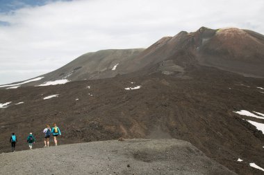 Bir grup turist güzel bir dağ manzarasında yürüyor.