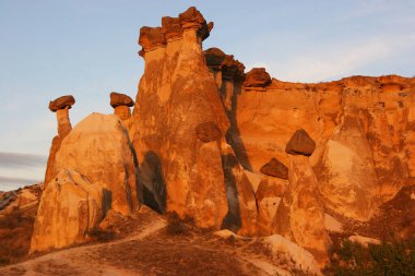 aşınmış peri bacaları ya da çıkıntılar, yukarıda dengelenen daha sert taşlar.