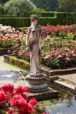 Çiçekleri, havuzu ve heykeli olan botanik bahçesi manzarası