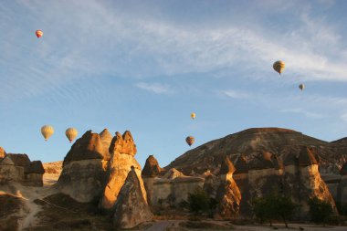 Turistlerle dolu sıcak hava balonları ulusal parkın üzerindeki volkanik bir arazide bunaltıcı manzaranın keyfini çıkarıyor.