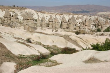 aşınmış yüksek bacalar ya da tepeler, daha sert taşlar üzerinde dengeleniyor ve daha yumuşak sütunu örtüyor.