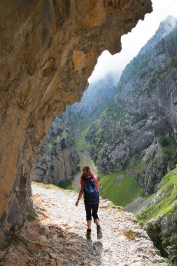 Kuzey İspanya 'da oyulmuş bir yürüyüş yolu ile dar ve sarp bir vadi boyunca iyi bilinen bir yürüyüş rotasındaki dağ yürüyüşçüleri..