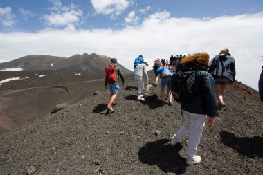 Bir grup turist güzel bir dağ manzarasında yürüyor.