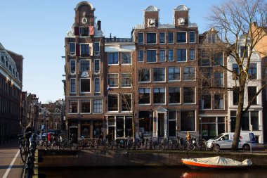Amsterdam kanal kemerinde sokak hayatı ve mobilyalarla tipik Hollanda mimari binaları