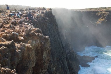 Bilinmeyen balıkçılar engebeli ve aşınmış yüksek kayalıklardan Atlas Okyanusu 'na bakan bir olta kamışlarıyla avlanırlar..