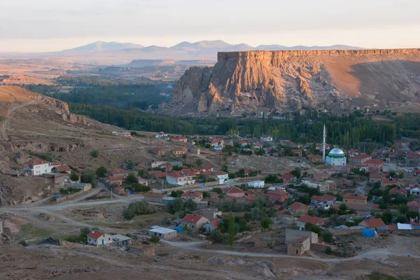 Tipik Kapadokyaca Vadisi köyü, taşlara kazınmış tarihi kaya konutları ve kiliselerle aşınmış dağın yanında.