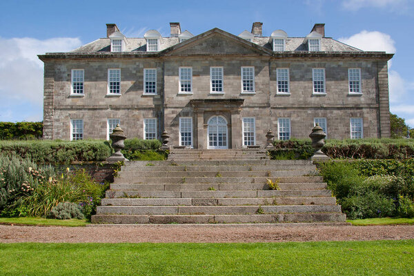 Английский загородный дом в сельской местности с большим лавочником и обширным садом с орнаментами