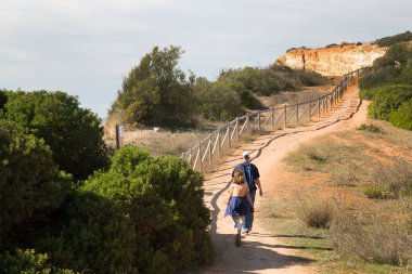 Deniz kıyısında yürüyen iki turist.
