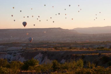 Turistlerle dolu sıcak hava balonları ulusal parkın üzerindeki volkanik bir arazide bunaltıcı manzaranın keyfini çıkarıyor.