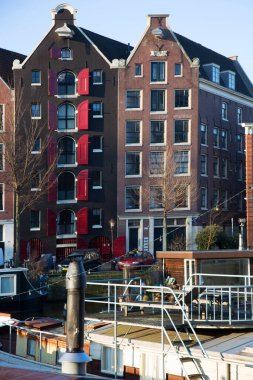 Amsterdam kanal kemerinde sokak hayatı ve mobilyalarla tipik Hollanda mimari binaları