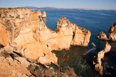 Tipik ve turistik engebeli ve çökmekte olan dengesiz Algarve kayalık kıyıları denizlerde kayalık tepeler, mağaralar, kemerler ve gizli cennet kumsalları