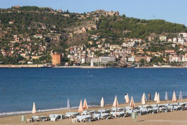 Güneşli halk plajı sahnesi ve denizdeki dağ