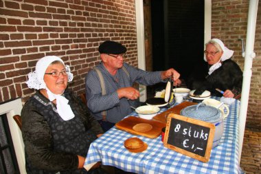 Waffle pişirme süreci. Geleneksel kostümlerle çalışan insanlar. 