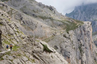 Kuzey İspanya 'da oyulmuş bir yürüyüş yolu ile dar ve sarp bir vadi boyunca iyi bilinen bir yürüyüş rotasındaki dağ yürüyüşçüleri..