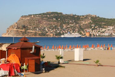 Güneşli halk plajı sahnesi ve denizdeki dağ