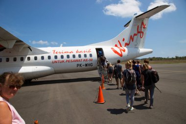Havaalanında gün ışığında uçağı olan bir grup insan.
