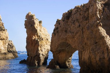 Tipik ve turistik engebeli ve çökmekte olan dengesiz Algarve kayalık kıyıları denizlerde kayalık tepeler, mağaralar, kemerler ve gizli cennet kumsalları