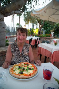 Restoranda pizza yiyen bir kadın.