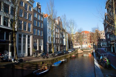 Amsterdam kanal kemerinde sokak hayatı ve mobilyalarla tipik Hollanda mimari binaları