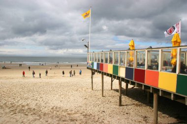 İnsanlar deniz sahilinde yürüyor ve dinleniyor.