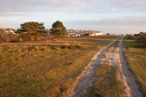 sunrise at shoreline with hiking trail and small village on top of cliff